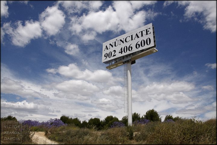Fotografía de un gran poste publicitario en medio del campo en el que aparece escrito "anúnciate"