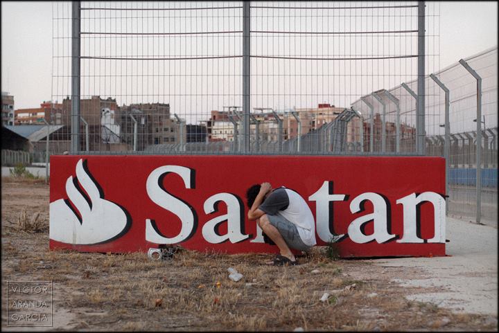 Autorretrato delante de un cartel publicitario del banco de Santander colocado de tal manera que en el cartel se lee la palabra "satán"