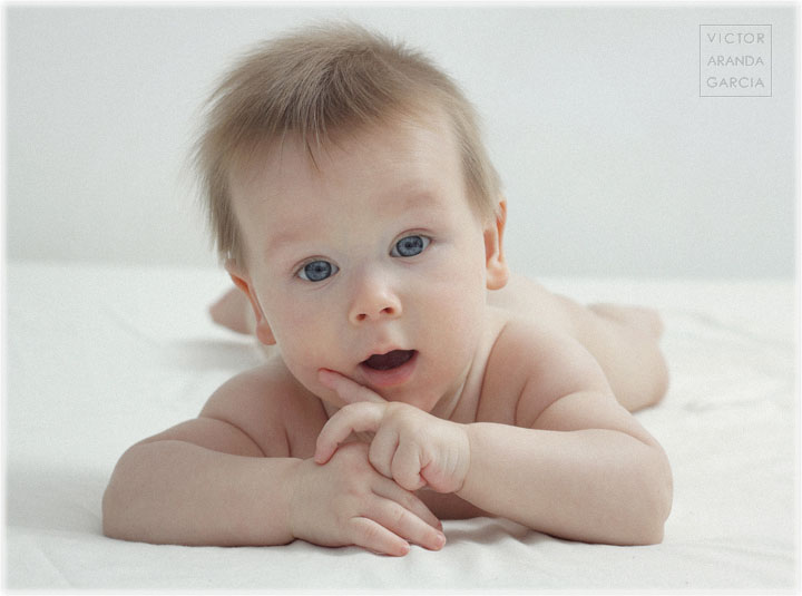 Fotografía de un bebé sobre una cama blanca