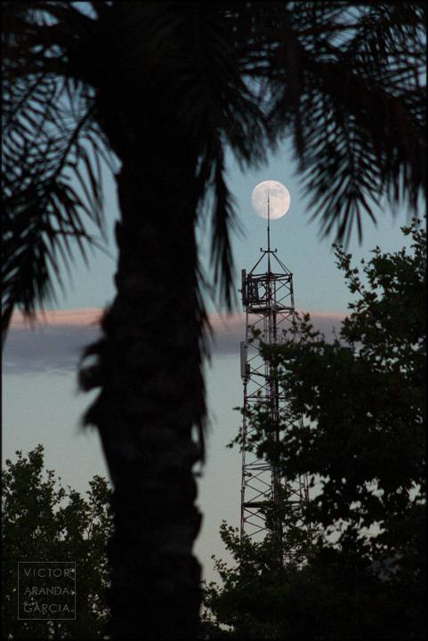 foto de la luna con una torre a contraluz