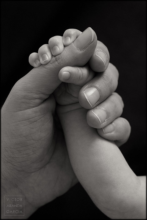 Fotografia en blanco y negro del brazo de un bebé cogido por la mano de su madre